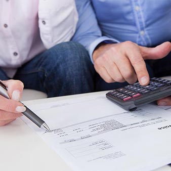 An image of two people using a calculator while reviewing a billing statement.