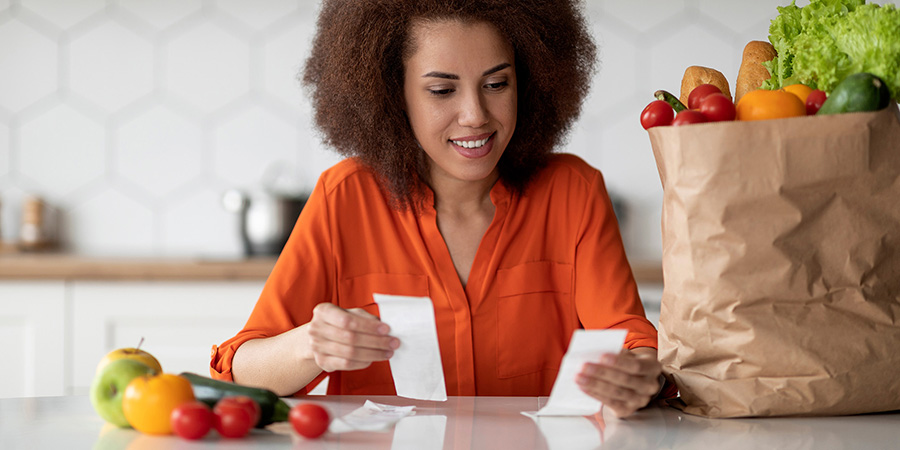 Lady Checking Bills In Kitchen After Grocery Shopping